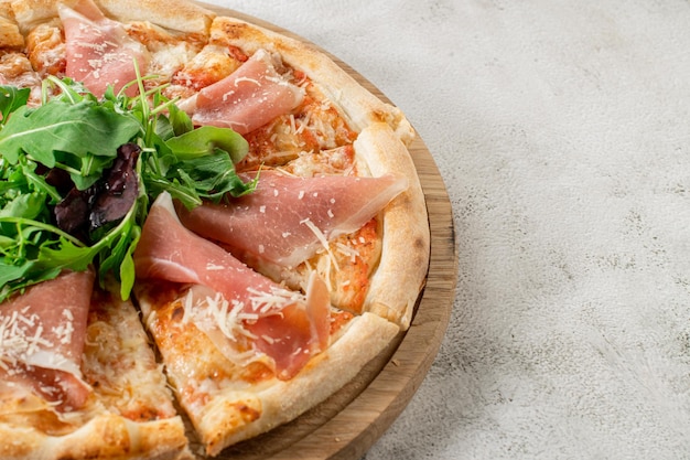 Fleischpizza mit Schinken und Käse auf dem weißen Betonhintergrund