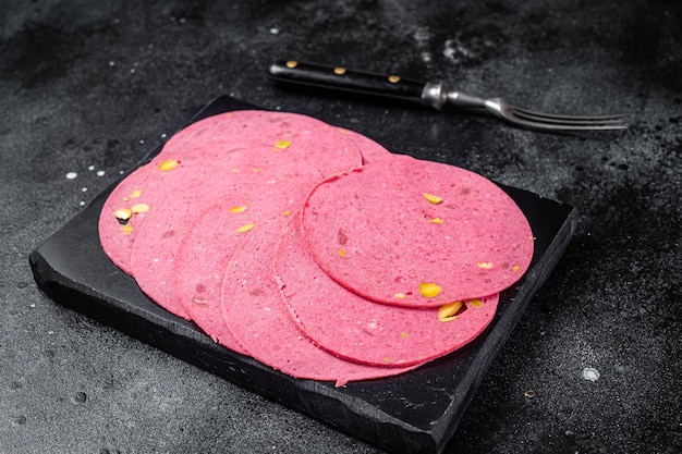 Fleischscheiben Salamiwurst mit Pistazien auf Marmorplatte Schwarzer Hintergrund Ansicht von oben