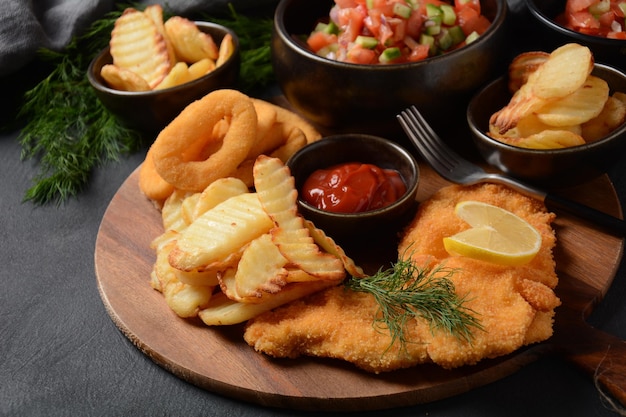 Fleischschnitzel und Bratkartoffeln mit Zwiebelringen frittierter Gemüsesalat