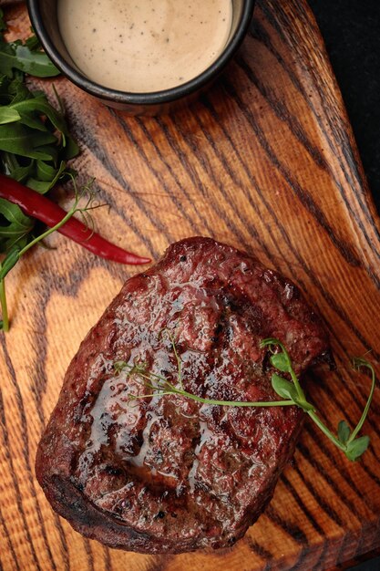 Fleischsteak auf dem Holzbrett auf dunklem Hintergrund