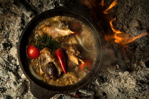 Fleischsuppe mit Gemüse auf brennenden Kohlen zubereitet. das Gericht wird auf Holzkohle gekocht und geräuchert