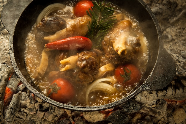 Fleischsuppe mit Gemüse auf brennenden Kohlen zubereitet. das Gericht wird auf Holzkohle gekocht und geräuchert