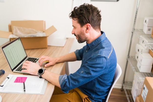 Fleißiger Geschäftsinhaber, der an seinem Schreibtisch sitzt und am Laptop arbeitet. Jungunternehmer, der versucht, im Startup-Geschäft erfolgreich zu sein