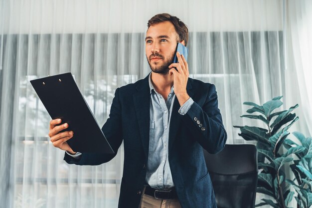 Fleißiger Geschäftsmann steht in einem modernen Büro und telefoniert