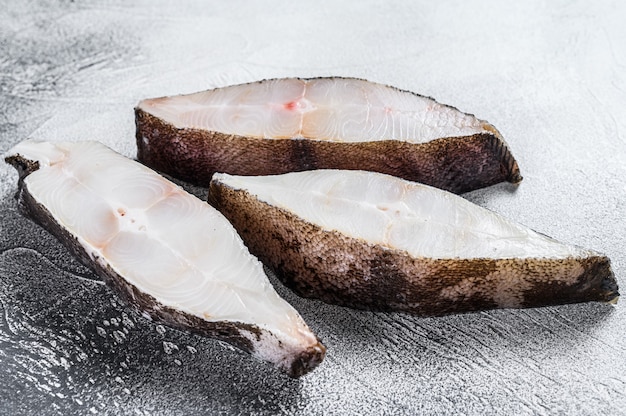 Fletán de pescado filete fresco crudo sobre la mesa de piedra. Fondo blanco. Vista superior.