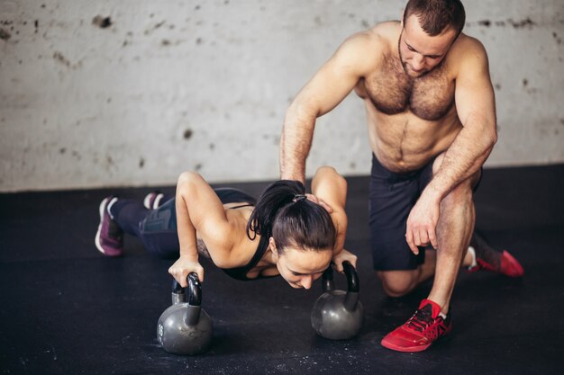 Flexão de força de flexão de homem e mulher treinador em um treino de fitness