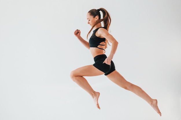 Flexibilidade do corpo jovem em roupas esportivas fazendo ginástica dentro de casa