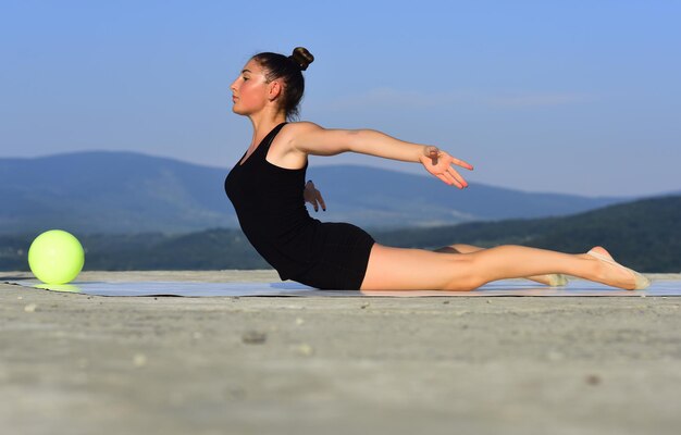 Flexibilidade na escola de ginástica de saúde de acrobacias e fitness e treino de energia da menina no céu azul...