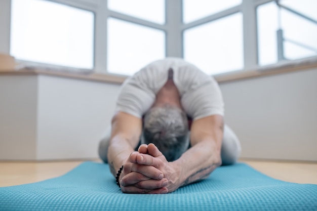Flexibilität. Ein reifer Yogi, der zu Hause trainiert und flexibel aussieht