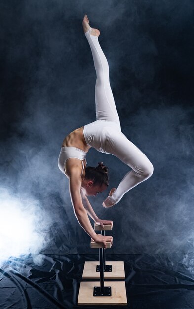 Flexible weibliche Akrobatin des Zirkuskünstlers, die Handstand tut