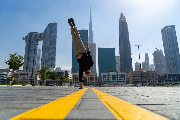 Flexibler Acrobat hält einerseits das Gleichgewicht mit dem verschwommenen Stadtbild von Dubai