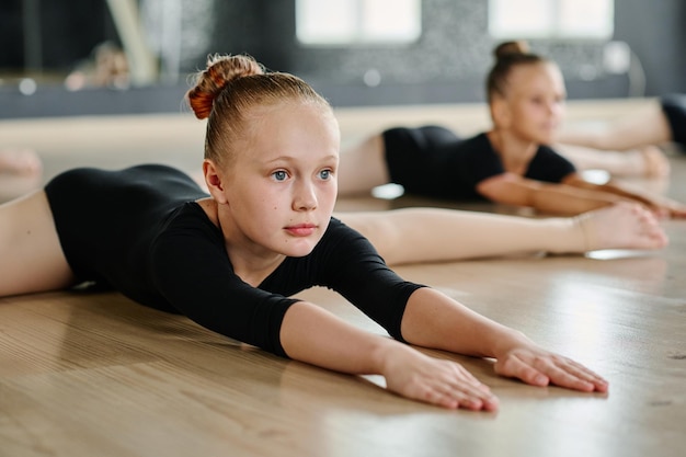 Flexibles Mädchen, das nach vorne schaut, während es die Arme in der Schnurhaltung beugt und streckt