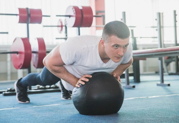 flexões de atleta em uma bola preta no ginásio