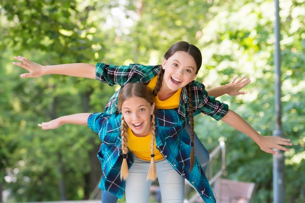 Flieg mit mir. Porträt von glücklichen Schwestern. kleine Kindermädchen im Hemd. Zwei junge lustige Hipster-Mädchen in trendiger Sommerkleidung. sorglose Kinder posieren im Freien. Positive Modelle. Lässiges Hipster-Outfit.