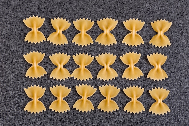 Fliege Pasta auf grauem Raum. Ungekochte Farfalle. Italienische nationale Küche. Kulinarischer Raum.