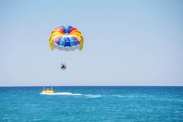 Fliegen auf einem Fallschirm hinter einem Boot in einem Sommerurlaub am Meer im Ferienort Türkei Parasailing aktiver Sport an schönen Sommertagen