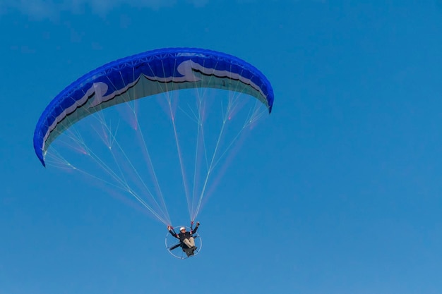 Fliegen mit Motorschirm in der Luft auf Hintergrund des blauen Himmels