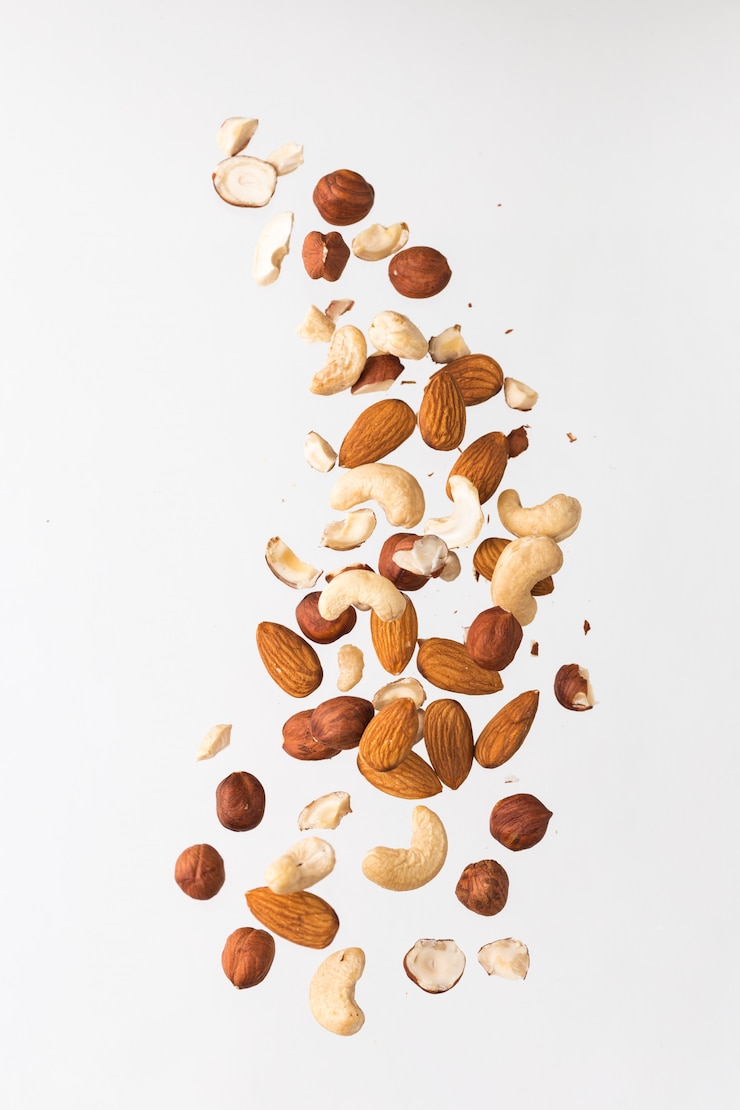 Foto fliegende nüsse auf grauem grund: mandeln, cashewnüsse und haselnuss