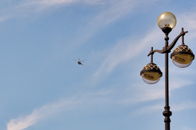 Fliegender Hubschrauber vor dem Hintergrund eines blauen Himmels mit Fichtenwolken. Blanko für Designer