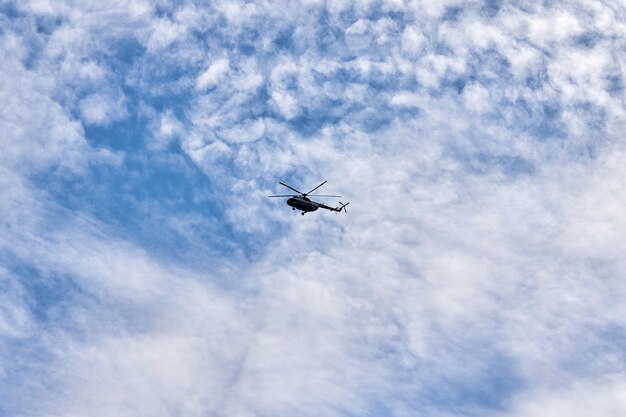 Foto fliegender hubschrauber vor dem hintergrund eines blauen himmels mit fichtenwolken