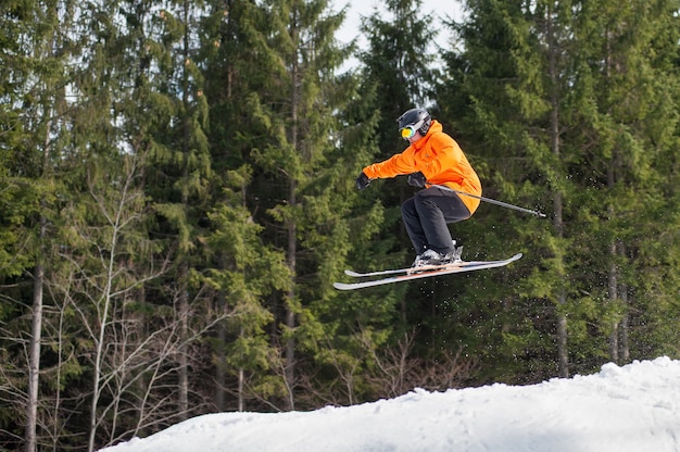 Fliegender Skifahrermann am Sprung von der Steigung der Berge