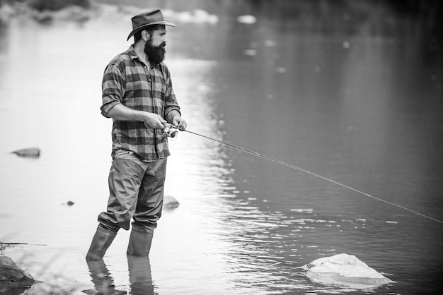 Fliegenfischen-Hobby des Mannes im karierten Hemdsportfischerfischer haben lange Stangen-schönen Tag, der in riv fischt