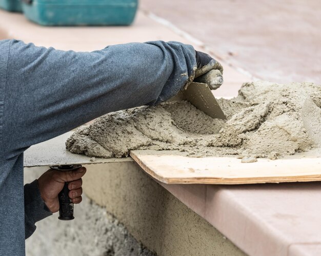 Foto fliesenbauer mischt nassen zement an bord auf der baustelle eines pools