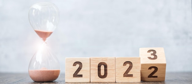 Flip block 2022 a 2023 texto con reloj de arena en la mesa Resolución tiempo plan objetivo motivación reinicio cuenta regresiva y conceptos de vacaciones de Año Nuevo