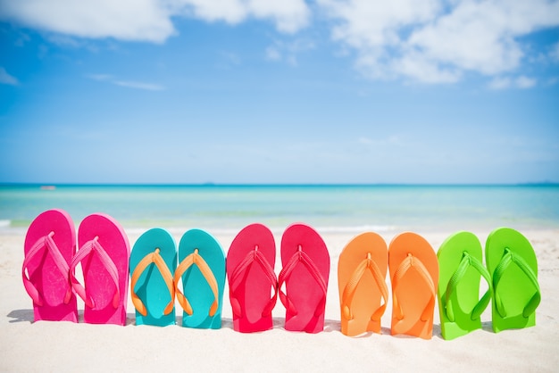 flip-flop colorido na praia arenosa, mar verde e céu azul de fundo para férias de verão co