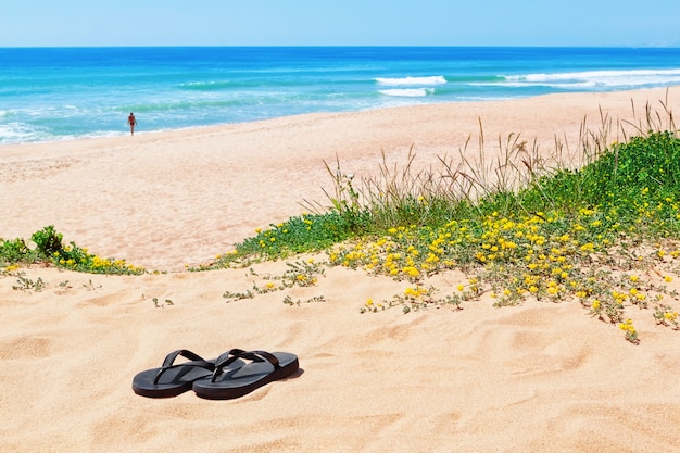 Flip-Flops auf dem Hintergrund des schönen Strandes und des Meeres.