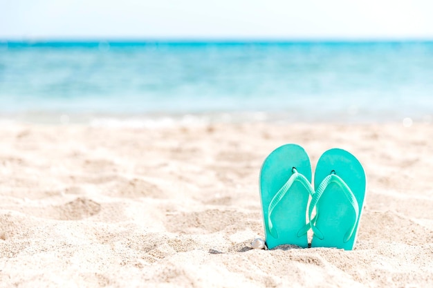 Flip-Flops, die an einem Sandstrand am Meer oder Ozean im Sand stecken