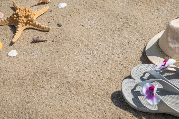 Flip-Flops, Hut und Muscheln an einem Sandstrand mit Rahmen. Sommer Hintergrund