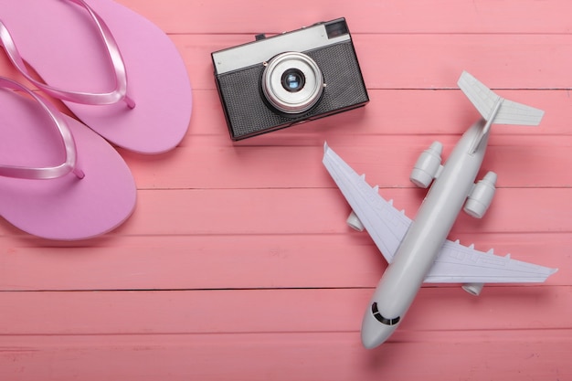 Flip Flops mit einer Kamera, Flugzeug auf einem rosa Holz. Reise-, Tourismus- oder Resortkonzept