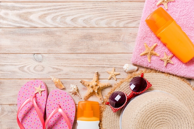 Flip-Flops, Strohhut, Seestern, Sonnencreme-Flasche, Bodylotion-Spray auf Holzhintergrund-Draufsicht. flach legen Sommer Strand Meer Zubehör Hintergrund, Reisekonzept.