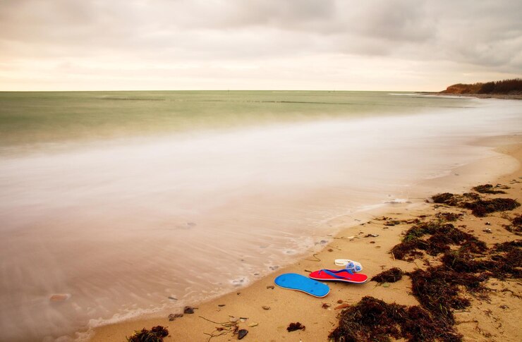 Foto flip-flops vermelhos azuis e óculos de natação brancos prontos para uso em praias pedregosas em quebra-mares de madeira