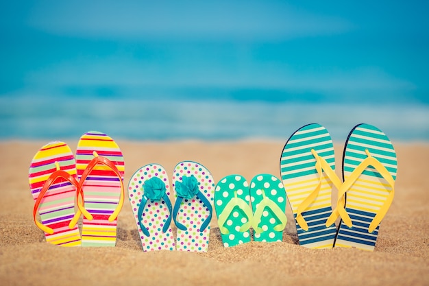 Flipflops am Sandstrand gegen blaues Meer und Himmel