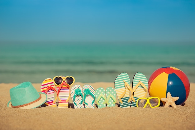 Flipflops en la playa de arena contra el cielo y el mar azul