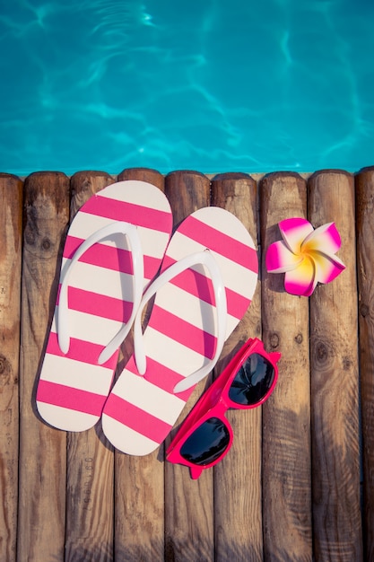 Flipflops sobre madera contra el concepto de vacaciones de verano de agua azul