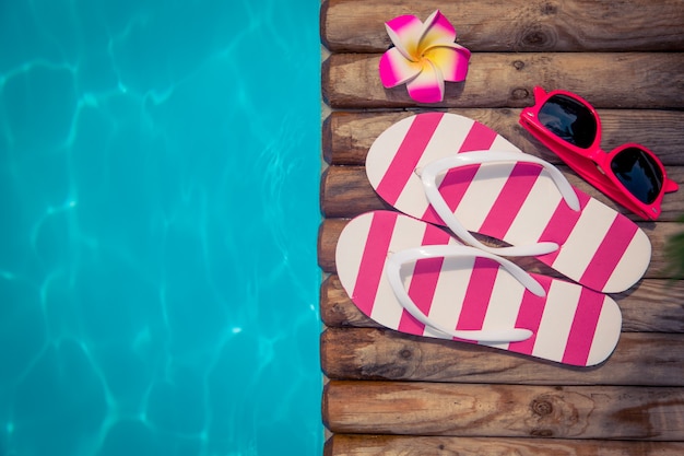 Foto flipflops sobre madera contra el concepto de vacaciones de verano de agua azul