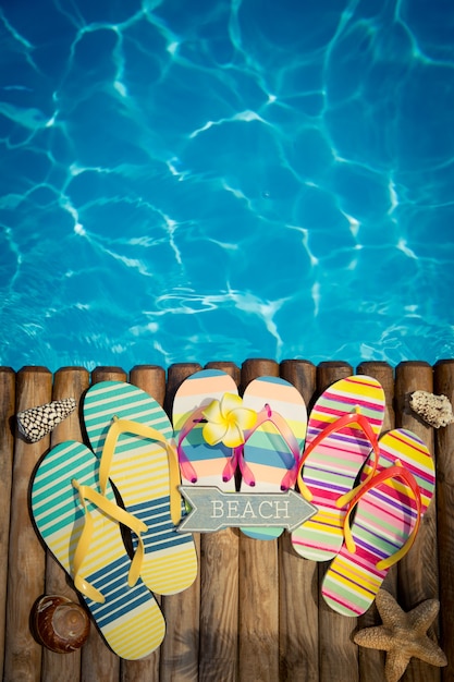 Flipflops sobre madera contra el concepto de vacaciones de verano de agua azul