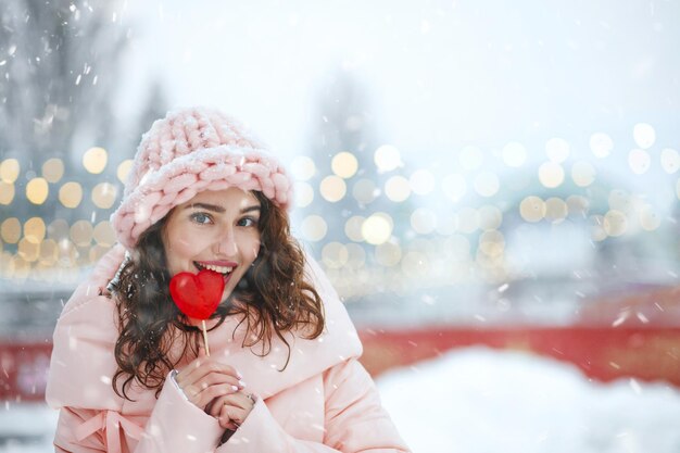 Flirty junge Frau, die roten Lutscher in einer Herzform hält. Platz für Text
