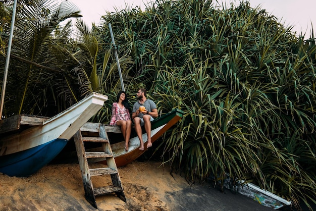 Flitterwochen. Verliebtes Paar am Meer, das Kokosnuss trinkt. Paar am Ufer der Paradise Island. Mann und Frau auf Bali. Entspannen Sie auf der Insel. Urlaubsromanze. Reise nach Asien. Glückliches Paar