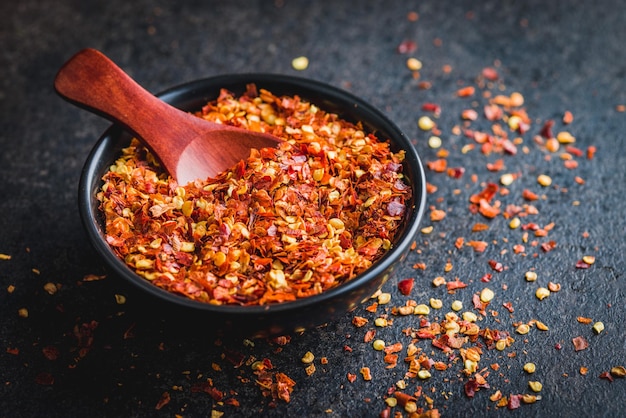 Flocos de chile seco Pimientos rojos triturados en un cuenco en la mesa negra