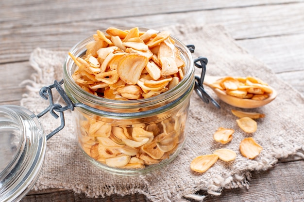 Flocos de alho secos ou chips de alho e alho cru em fundo de madeira velho