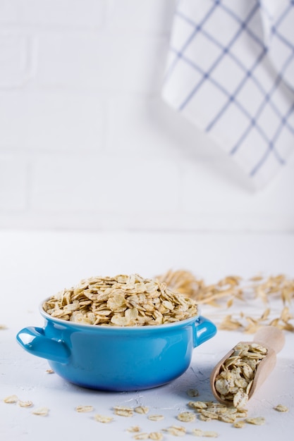 Flocos de aveia em uma tigela azul na mesa da cozinha