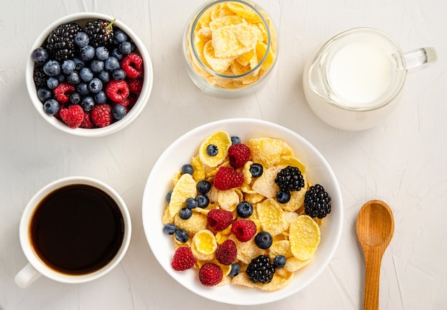 Foto flocos de milho com leite e frutas frescas em um fundo branco. conceito de pequeno-almoço ou lanche. postura plana. vista de cima.