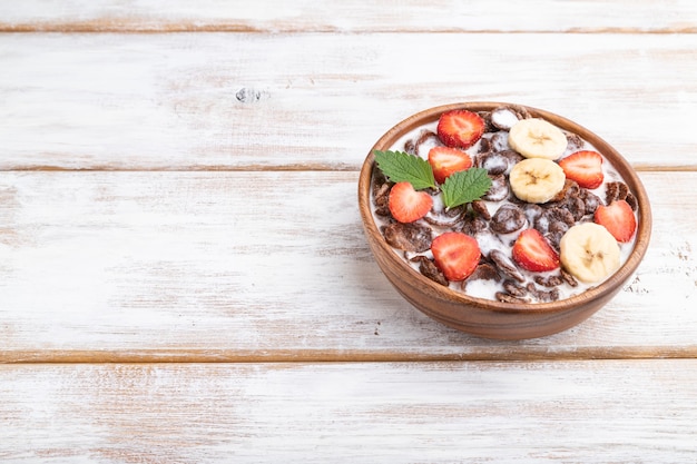 Flocos de milho de chocolate com leite e morango em uma tigela de madeira