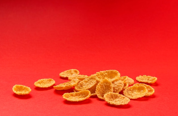 Flocos de milho isolados em um fundo de cor vermelha, pilha de cereal matinal tradicional, profundidade de campo total