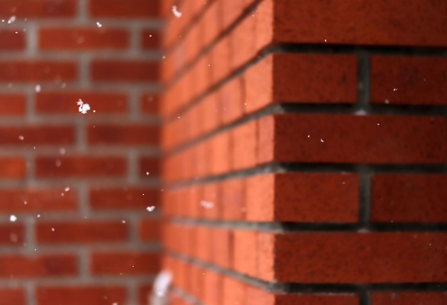 Flocos de neve caindo na frente da parede de tijolos