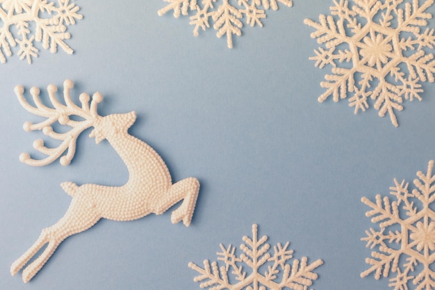 Flocos de neve e veados para decoração de ano novo em um fundo azul com espaço para layout de texto de Natal
